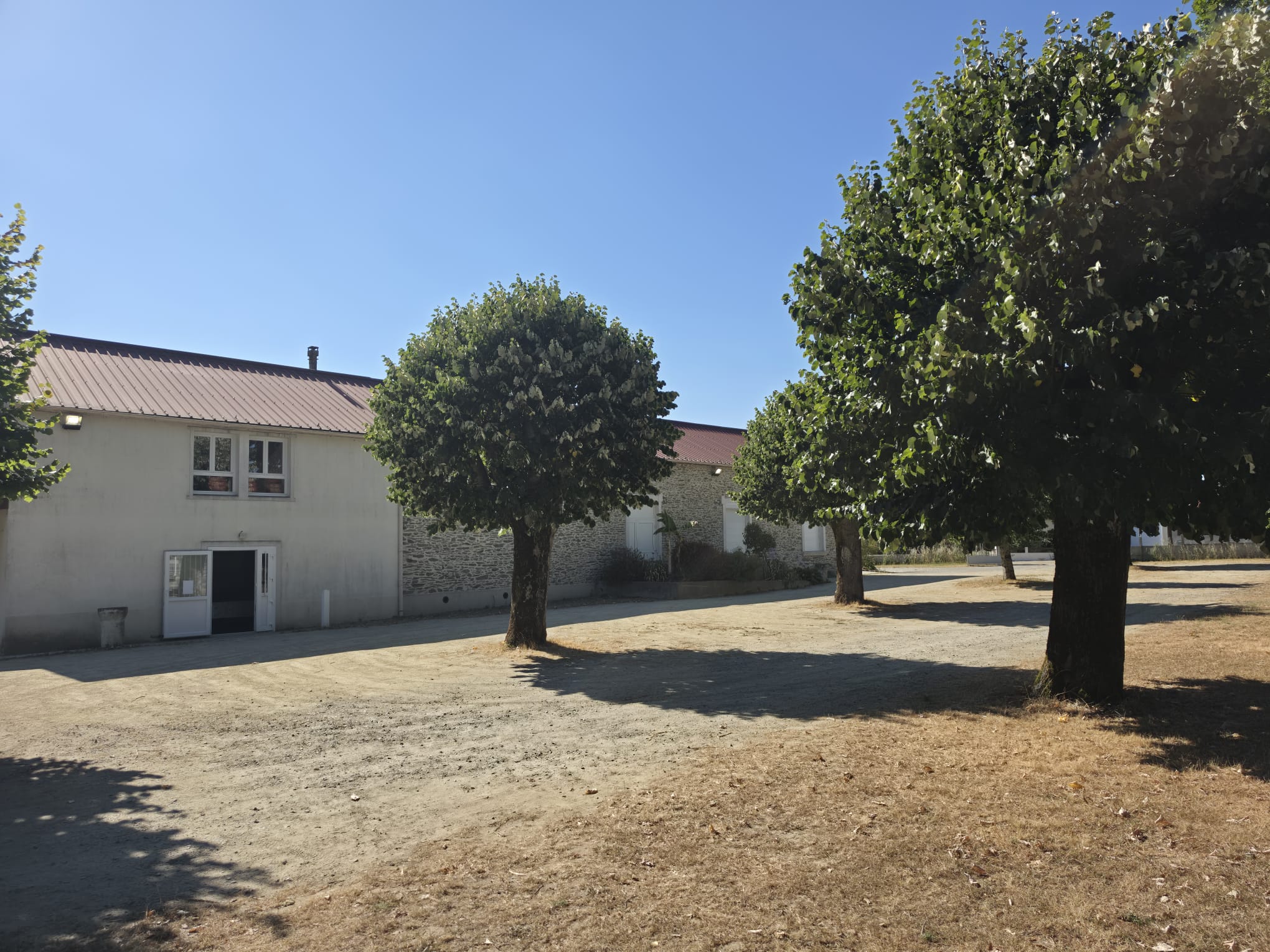 Vue de côté de la salle Jean-Noël Prin entourée d'arbres